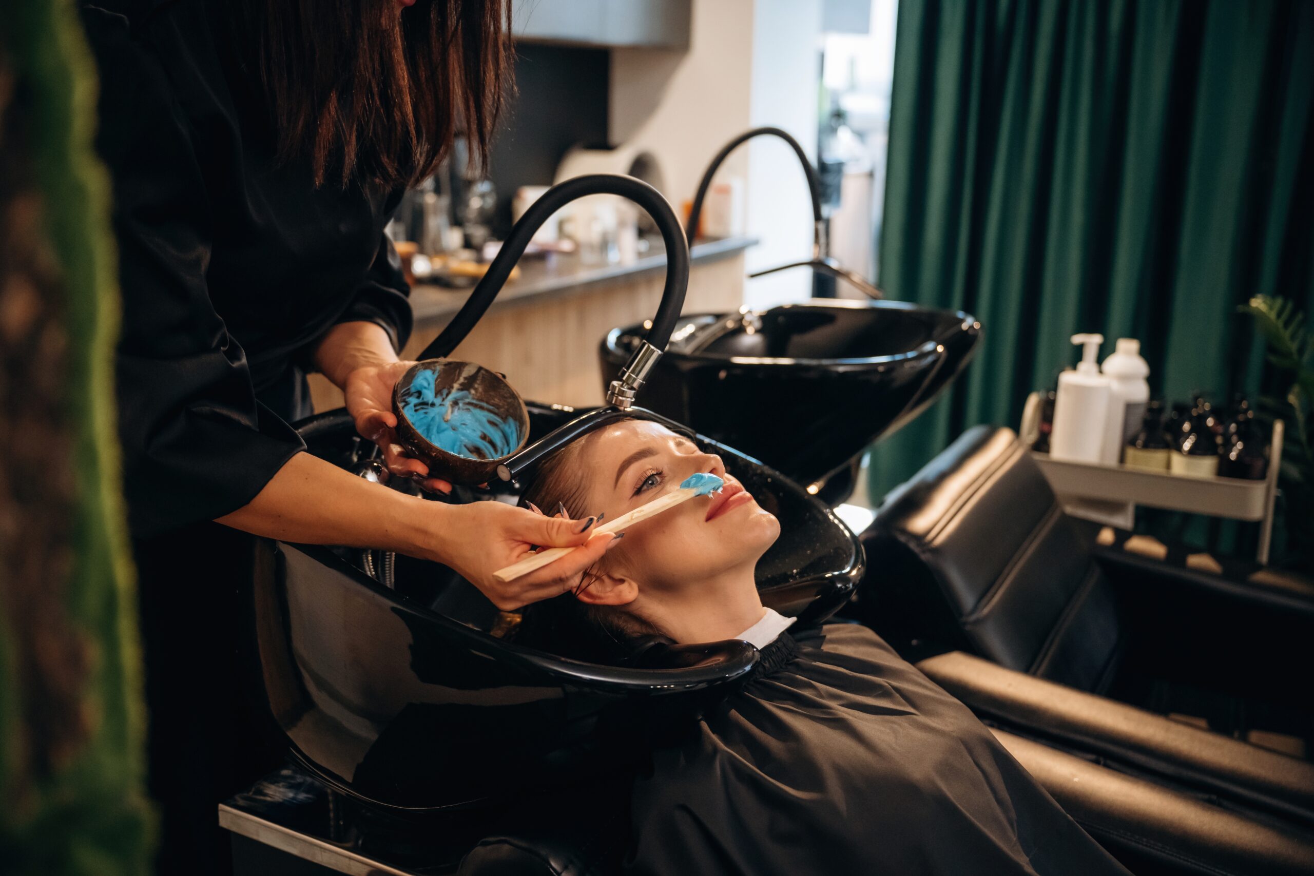 Hair coloring, blue. Woman is in a beauty salon with hair stylist.